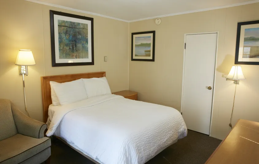 Plush white linens on a queen bed in a yellow walled room at The Ashley.