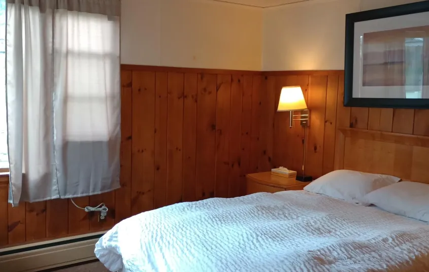 Plush white linens on a queen bed in a wood paneled room at The Ashley.