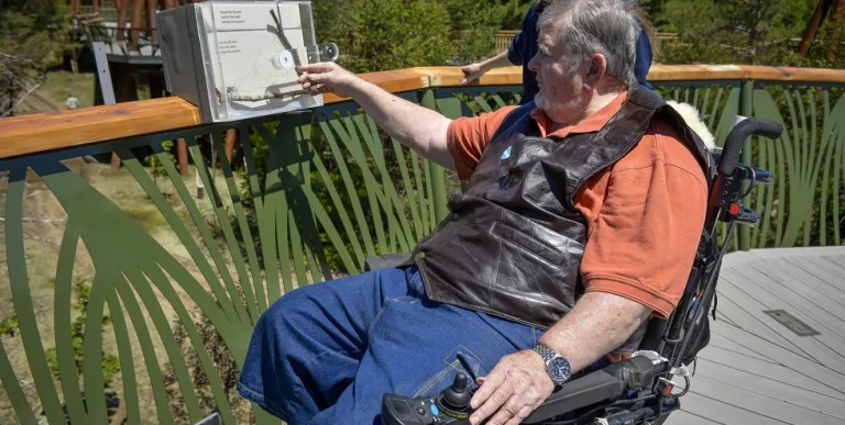 A man who uses a wheelchair stops along The Wild Walk to read a plaque