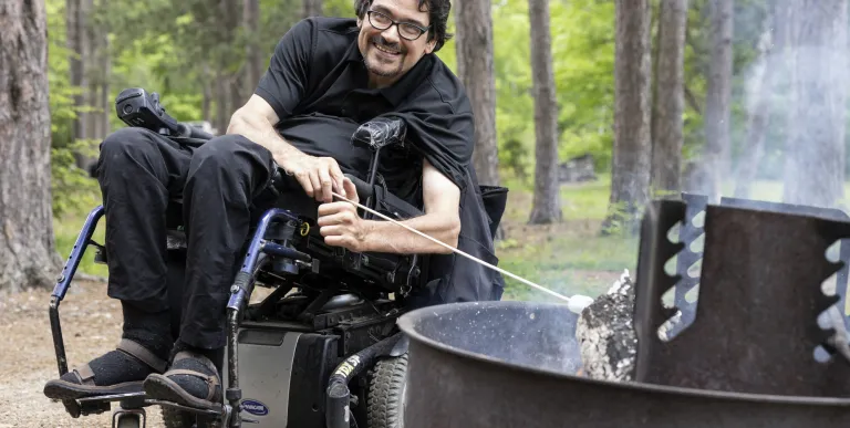 A man in a wheelchair roast a marshmallow.