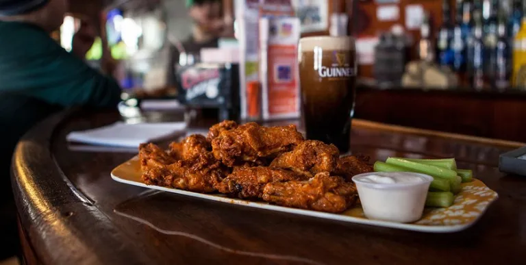 Chicken wings and guiness in a glass.