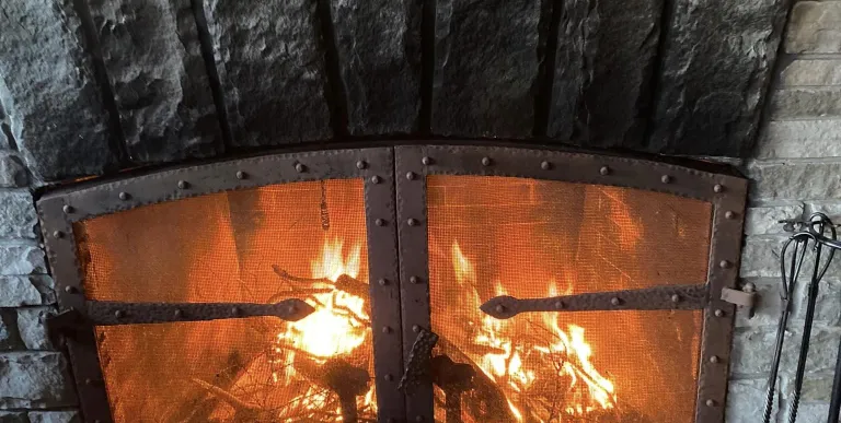A fire burns behind the black metal grate in the stone fireplace.