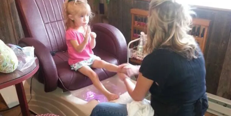 A little girl sits in a pedicure chair.