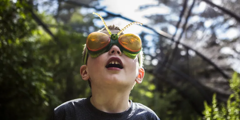 Kid wears bug glasses in the butterfly house at Paul Smiths VIC