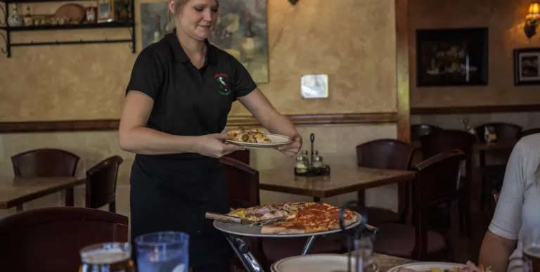 A waitress brings pizza to the table