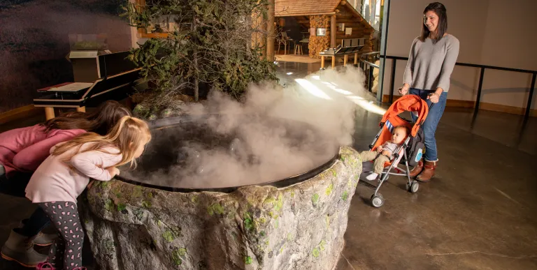 Two children play a game throwing snowballs into buckets set up on a suspended walkway on the Wild Center's Wild Walk