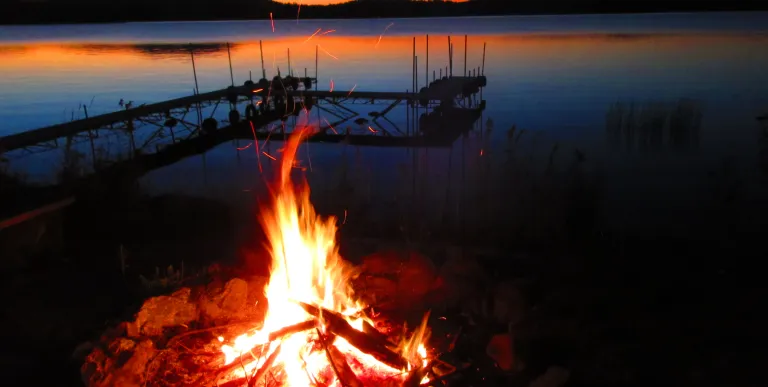 A bon fire by the lake with the red sunset.
