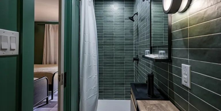 Emerald green tiles with white grout in the walk in shower.