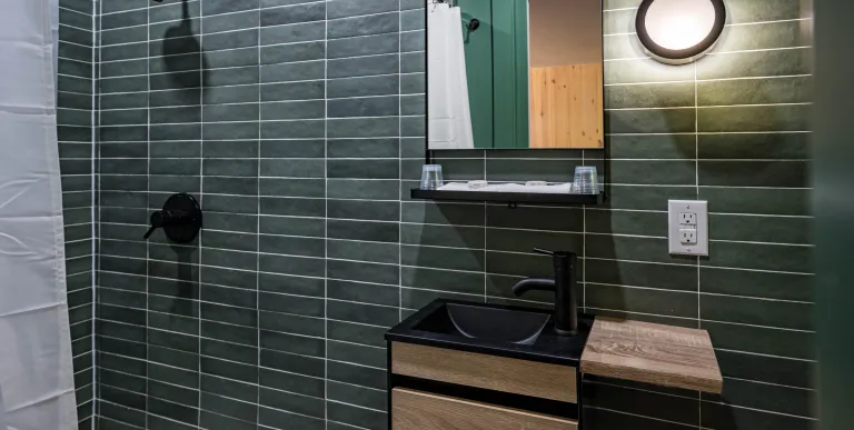 Emerald green tiles with white grout in the and dark vanity.