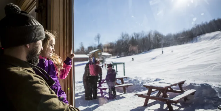 A father holds his daughter at the Pisgah base lodge
