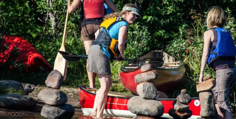 A smiling woman in a life jacket ready to board a boat.