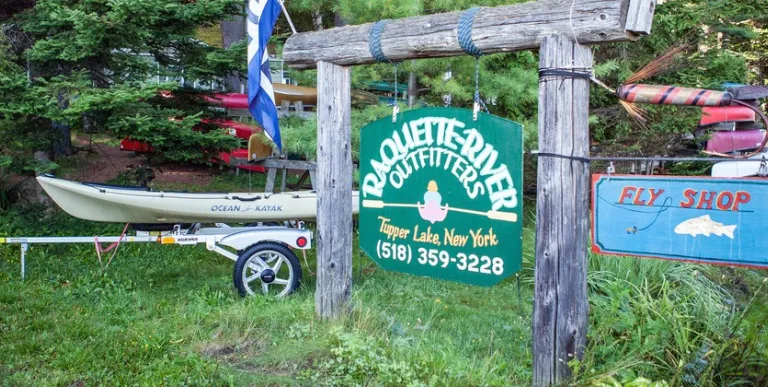 The green sign for Raquette River Outfitters