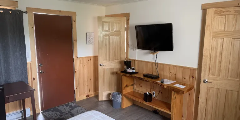 The entry way to a room with knotty pine wainscoting on the walls at Tupper Lake Motel.
