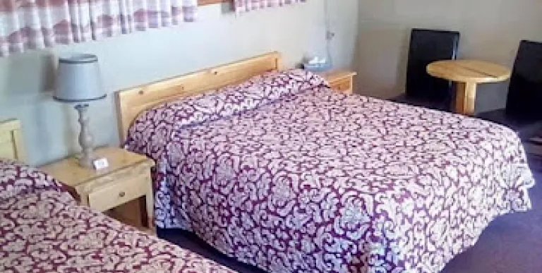 A two queen room with window and red and white bedding.