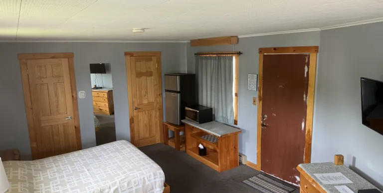 A king size bed in a room with dusty salmon walls at the Tupper Lake Motel.
