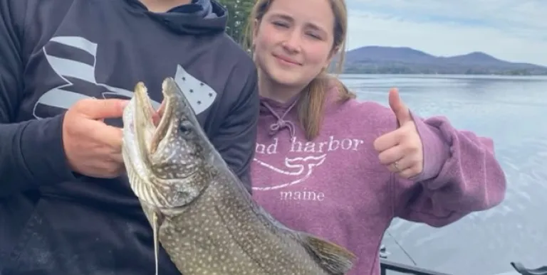 A man and woman hold a large fish and give a thumbs up.