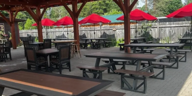 Rows of picnic tables under the covered roof of the brick patio at Raquette River Brewing.