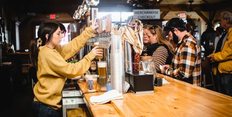 A beer is poured from the many tap handles as patrons wait on the other side of the bar
