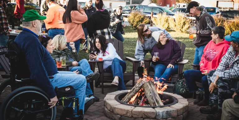 People enjoying nice weather on the accessible brick patio with fire ring.