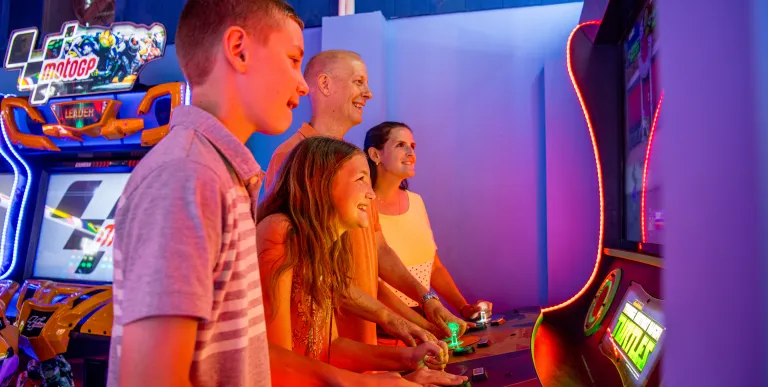 Family gathers around the arcade game.
