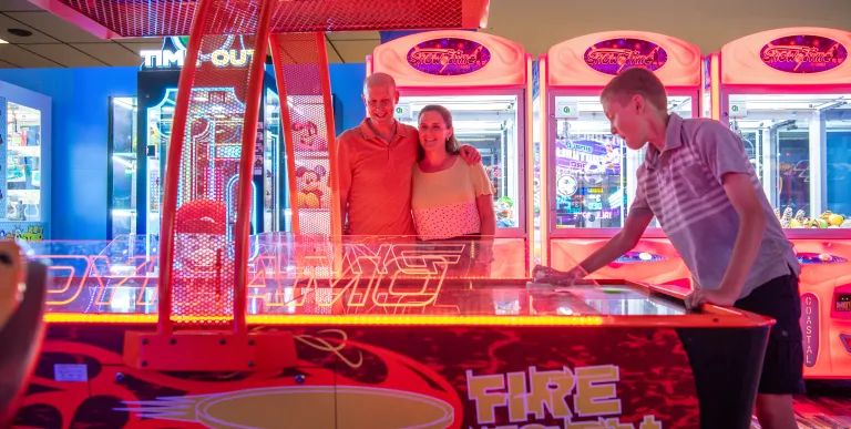 People gather around the air hockey table to watch the match.
