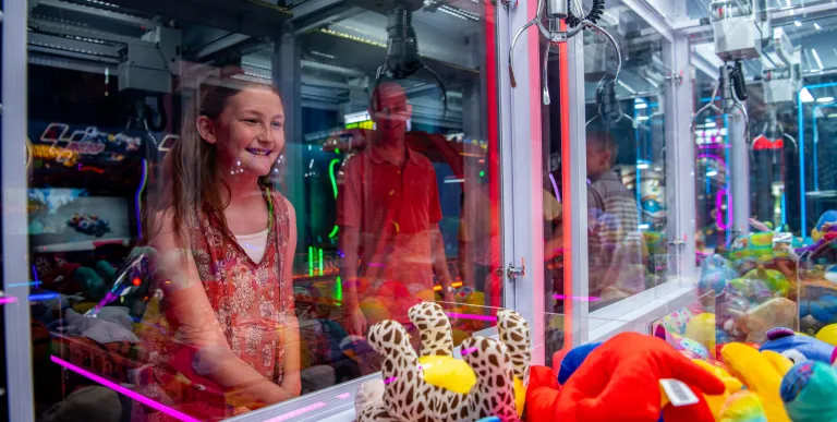 A girl uses the the claw machine for a prize.