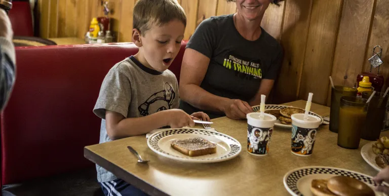 A smiling family enjoys a meal in a booth.