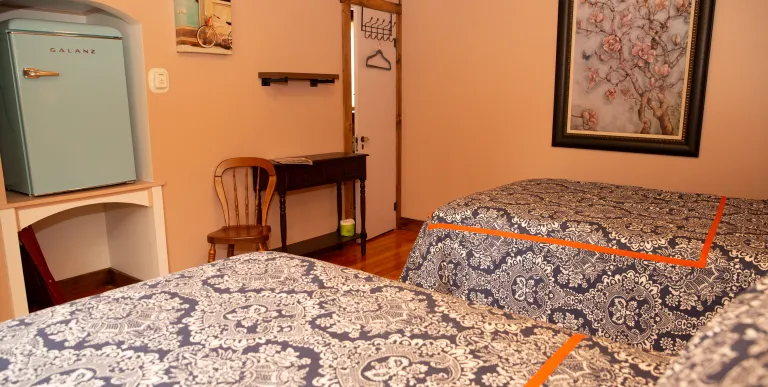 The white and blue bedding in a two queen room with small dining table.