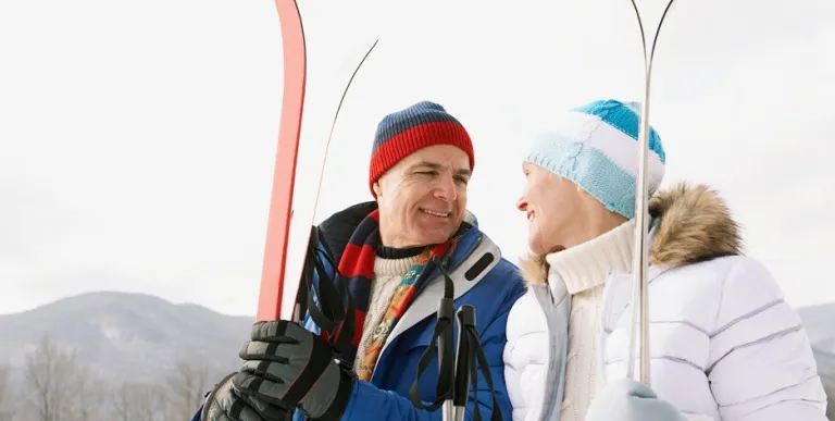 A smiling couple holding snow skis