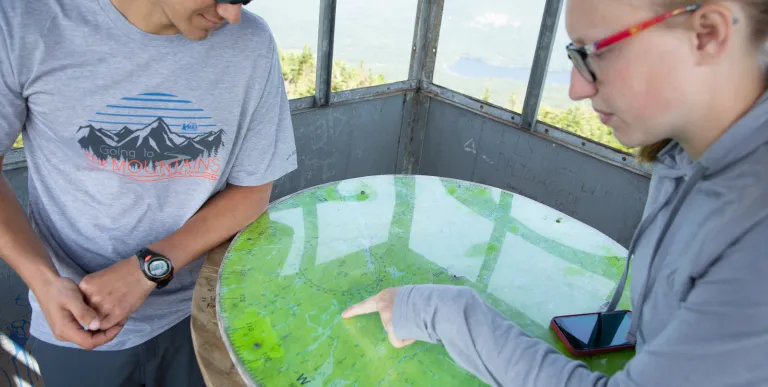Two hikers looking at a map in a firetower cabin