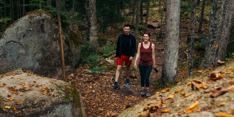 Two hikers approaching large rocks