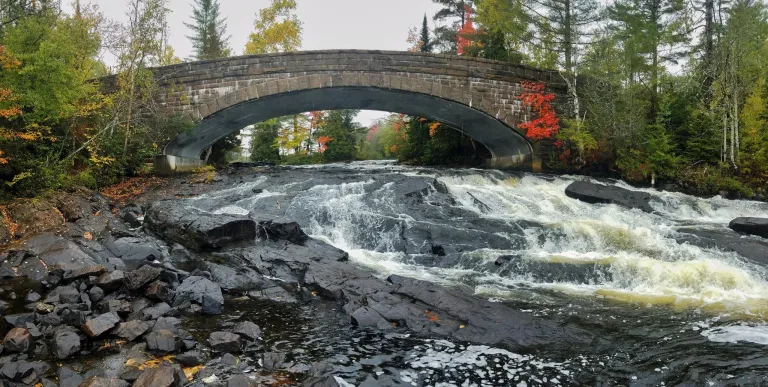 The arching bridge over Bog River Falls