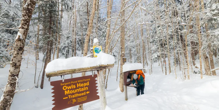 A snowshoer signs into a trailhead register
