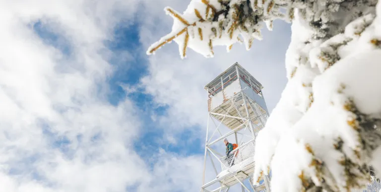 A hiker on the wintry firetower of Owls Head Mountain