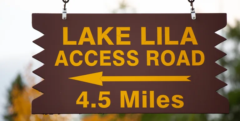A wooden sign with yellow lettering for Lake Lila