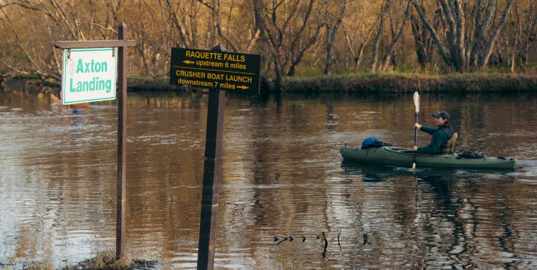 A kayaker going by a sign for Axton Landing