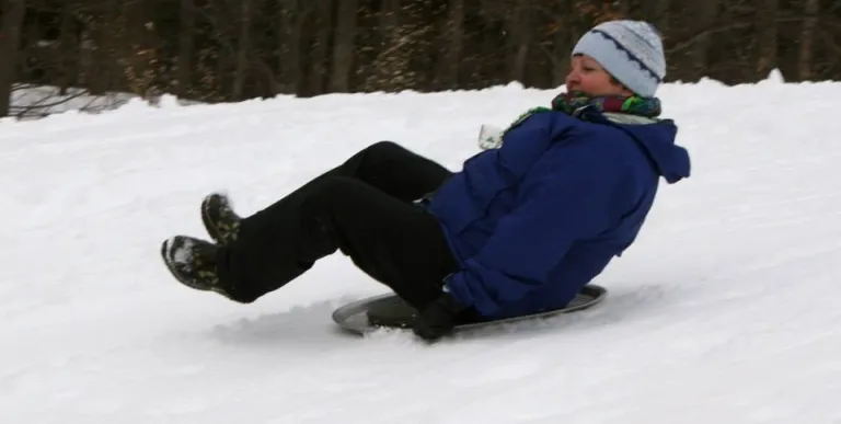 Families gather and play on the groomed sledding hill.