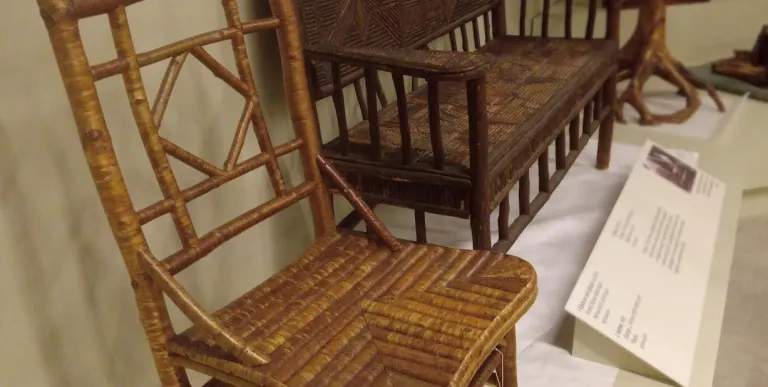  a large sign with the name and a massive wooden chair by the sidewalk