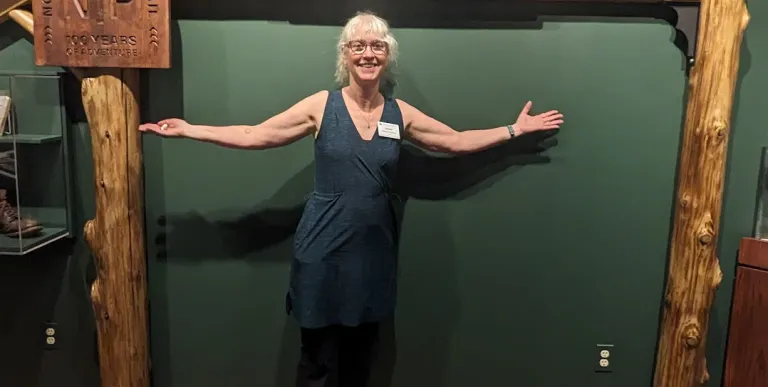 A woman smiles under a wooden arch against a green wall where plaques describing the NPT are displayed