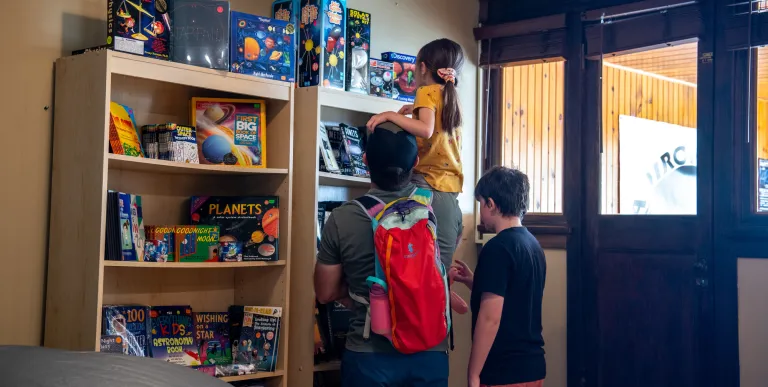 Kids climb to see the astronomy themed toys on a shelf