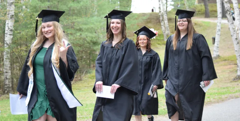 Smiling graduates walk by.