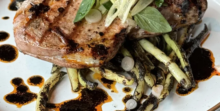 A perfectly grilled pork chop with seasoned wax beans