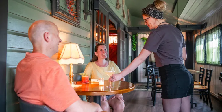 waitress placing a cocktail for a mid age couple