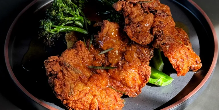 Beautifully fried and seasoned chicken plated with broccolini