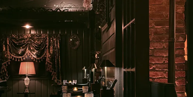 The dark and moody seating area with crystal glasses and warm lighting.