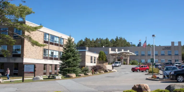 The big brick building and parking area of Adirondack Health Saranac Lake.