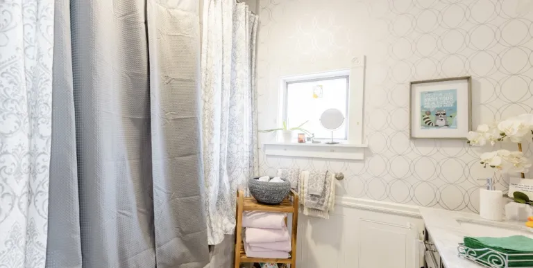 A bright white bathroom with light blue accents and orchids