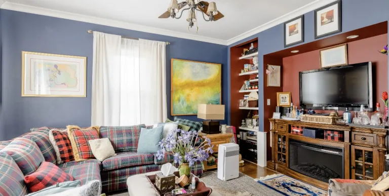 A comfortable blue living room with tv and fireplace.