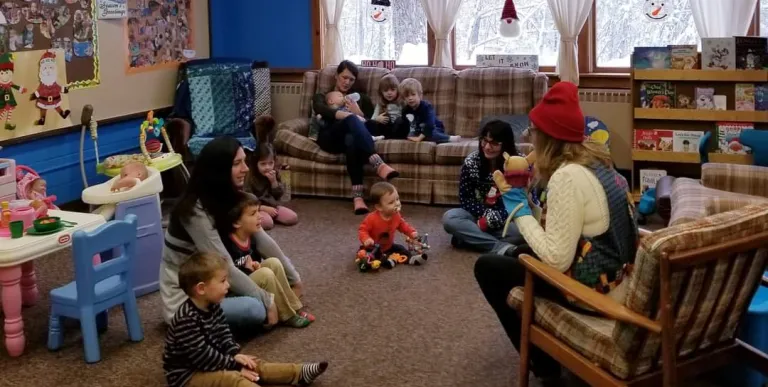 Families sit on the carpet and couches at story time.