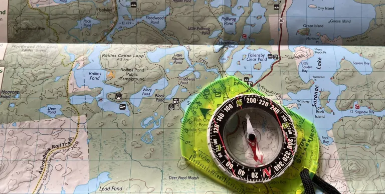 A map with a compass laying on top.